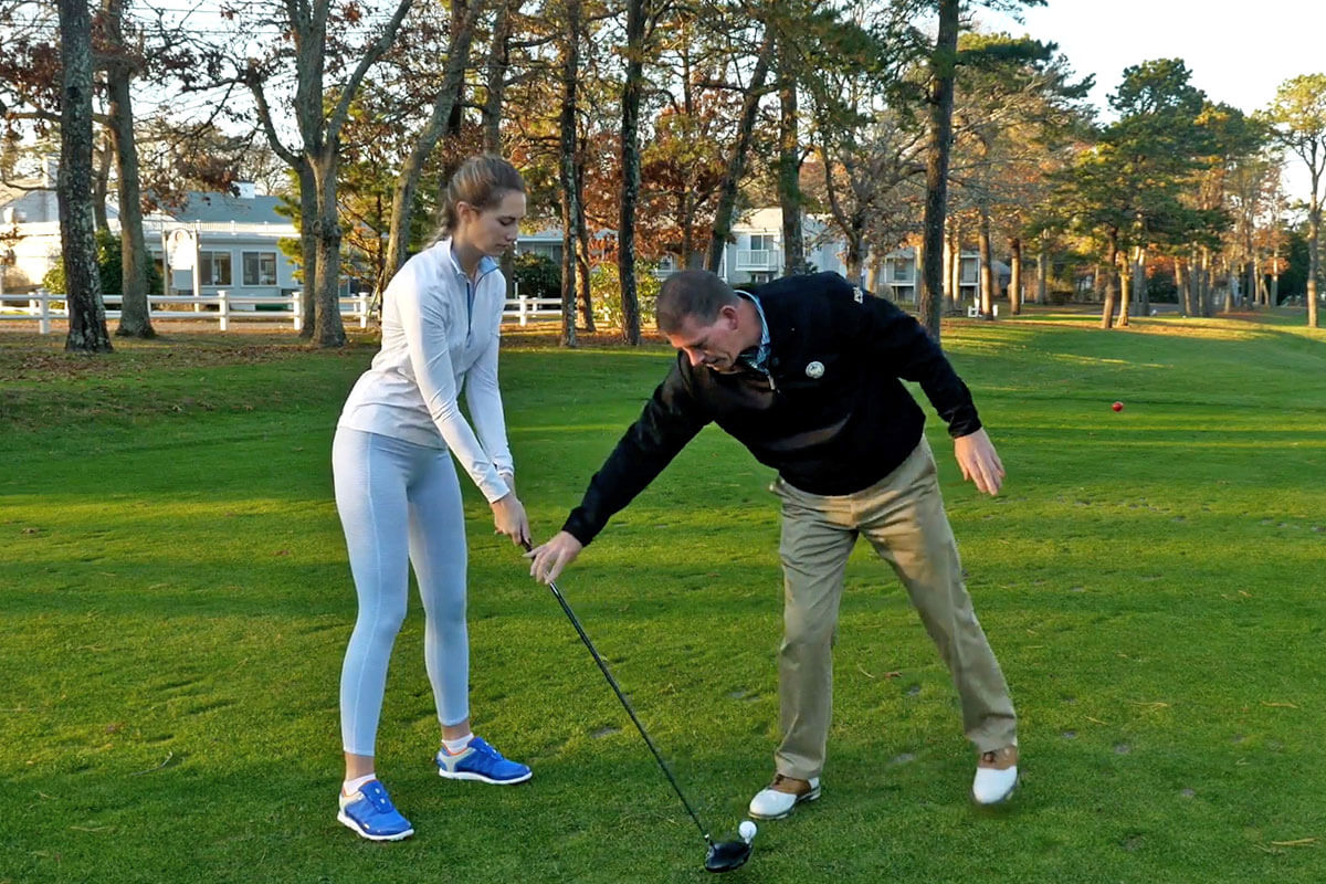 golf pro giving a lesson to a woman teeing off at Blue Rock Golf Course