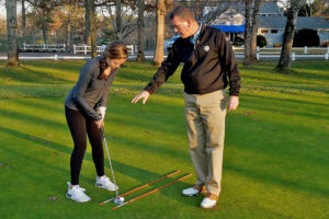 golf pro teaching a junior golfer a putting drill