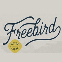 The image shows the word Freebird in a bold, cursive font with a yellow circle below containing the words Motor Lodge in uppercase letters. The background is light gray.